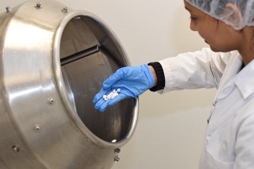 Lab technician mixing medication in advanced drum for medicine manufacturing